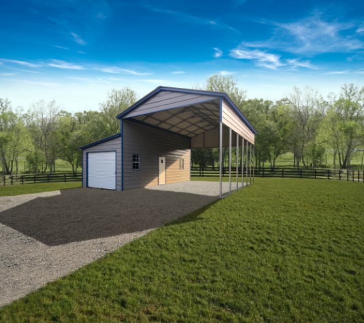 A metal barn with a carport on a grassy field under a blue sky.
