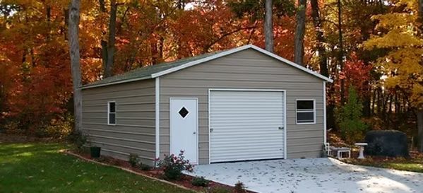 Tan garage with a white door and autumn trees in the background.