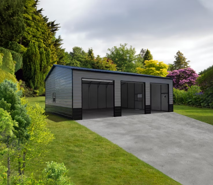 Gray metal three-bay garage with open doors on a concrete driveway, surrounded by greenery.