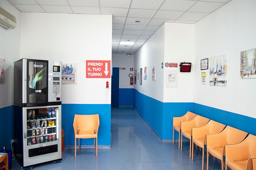 Una sala d'attesa con distributore automatico e sedie