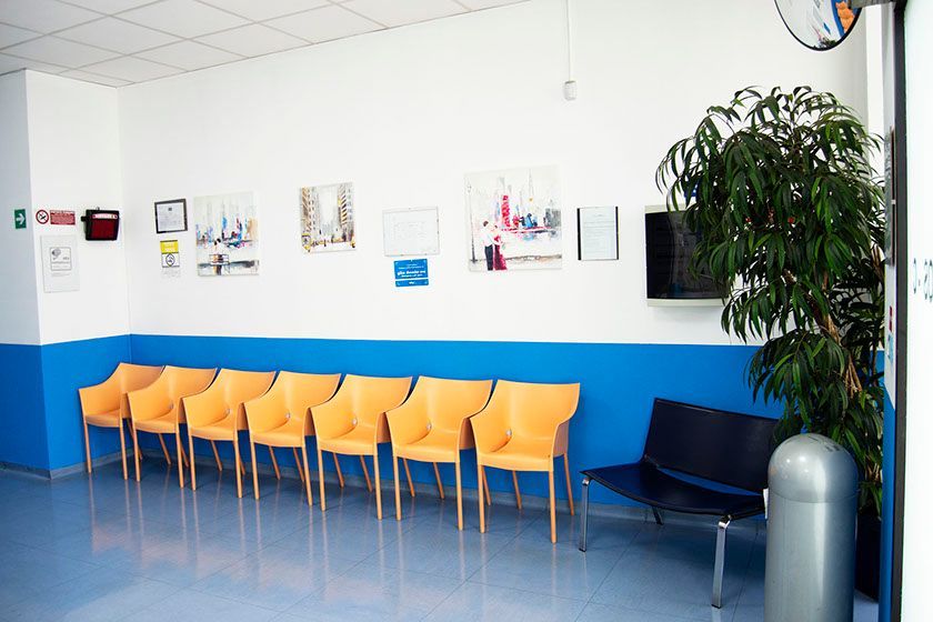 Una sala d'attesa con sedie gialle e una panca nera