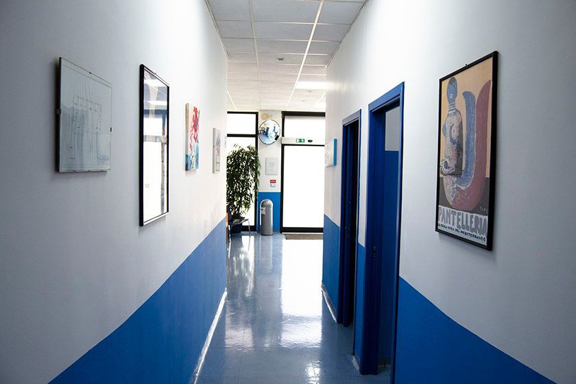 Un lungo corridoio con pareti e porte blu e bianche