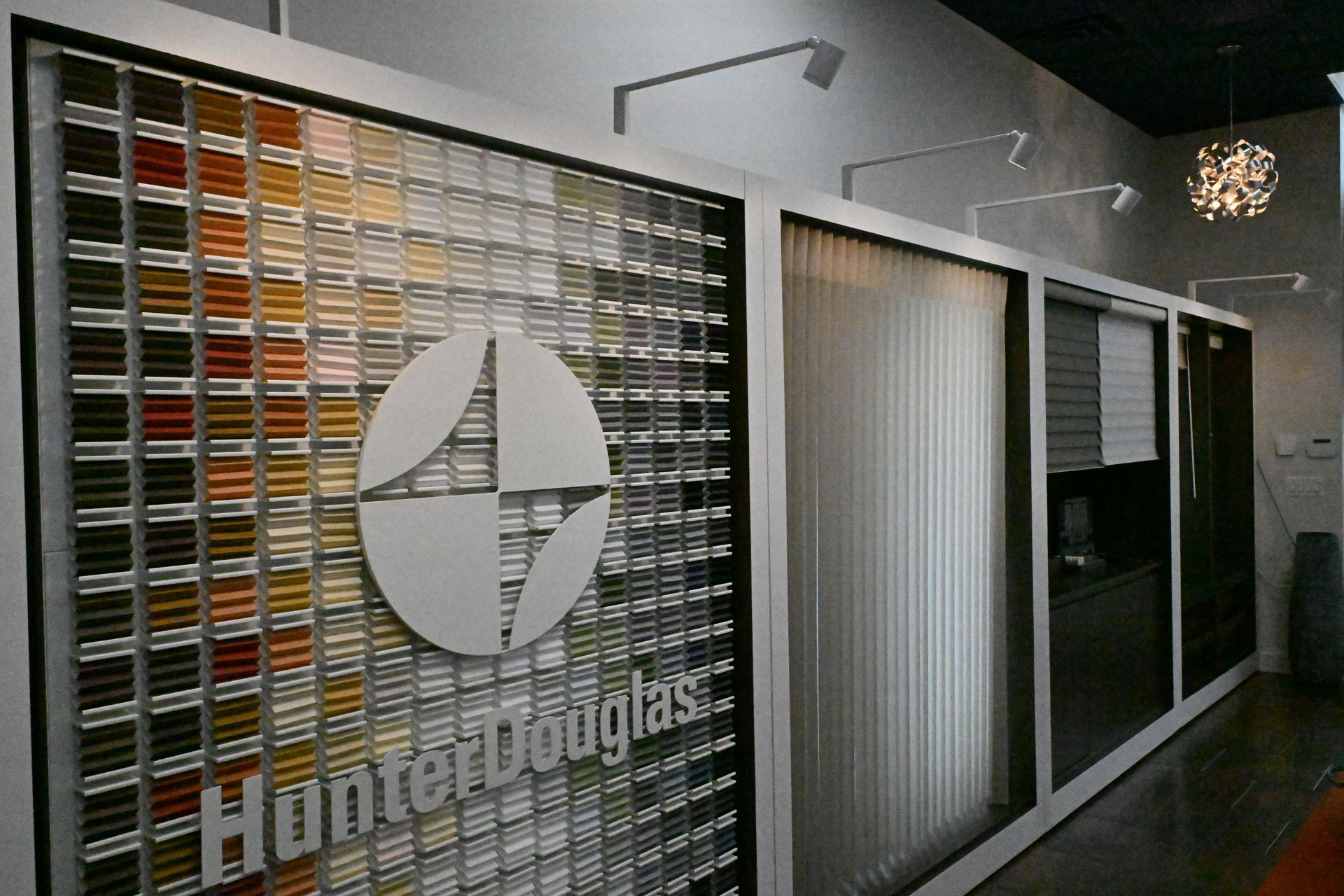A Hunter Douglas showroom display featuring fabric color swatches and vertical window blinds.