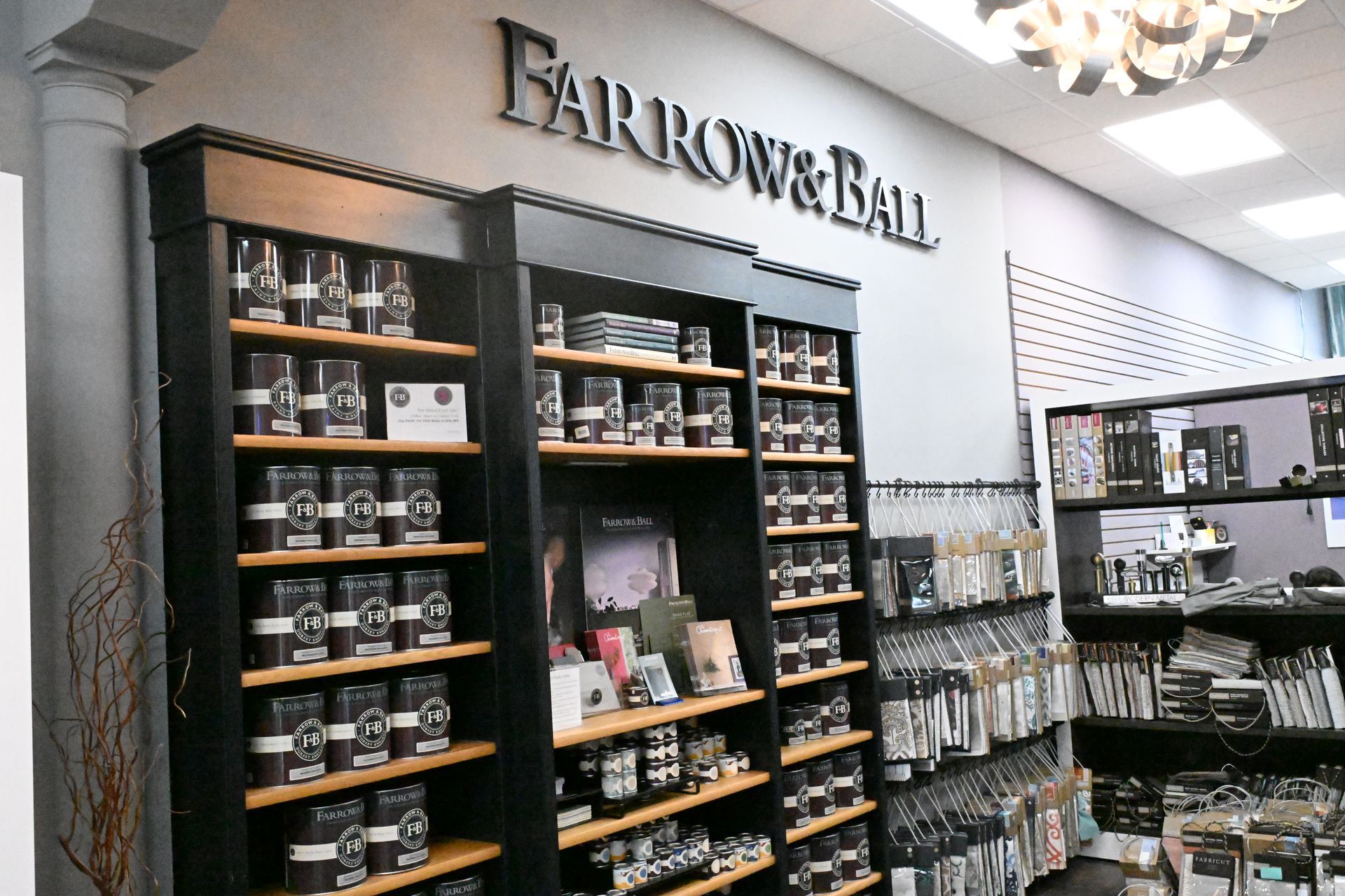 Display shelves stocked with Farrow & Ball paint tins in a retail store setting.