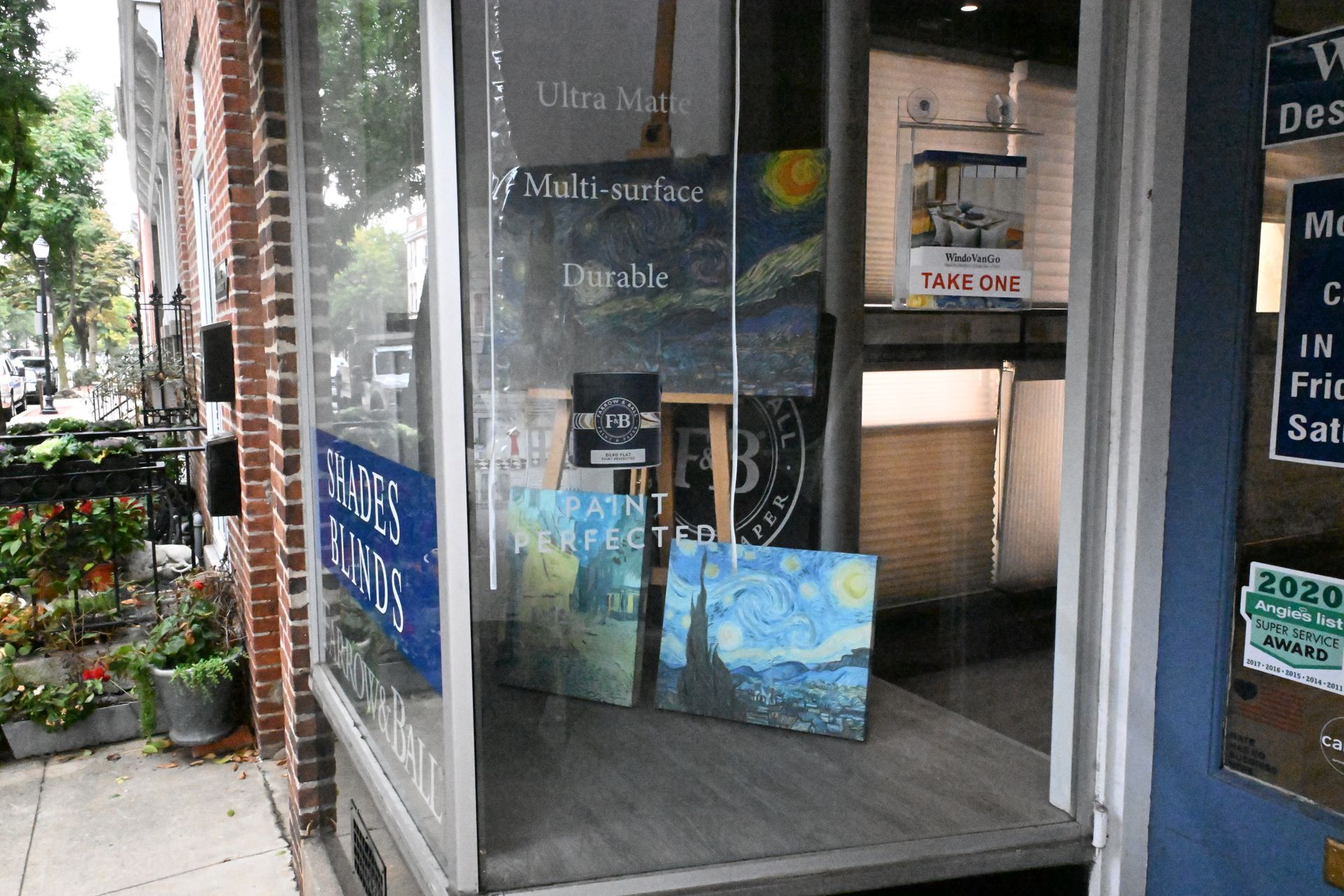 Storefront window displaying several landscape paintings inspired by Van Gogh, viewed from the sidewalk.