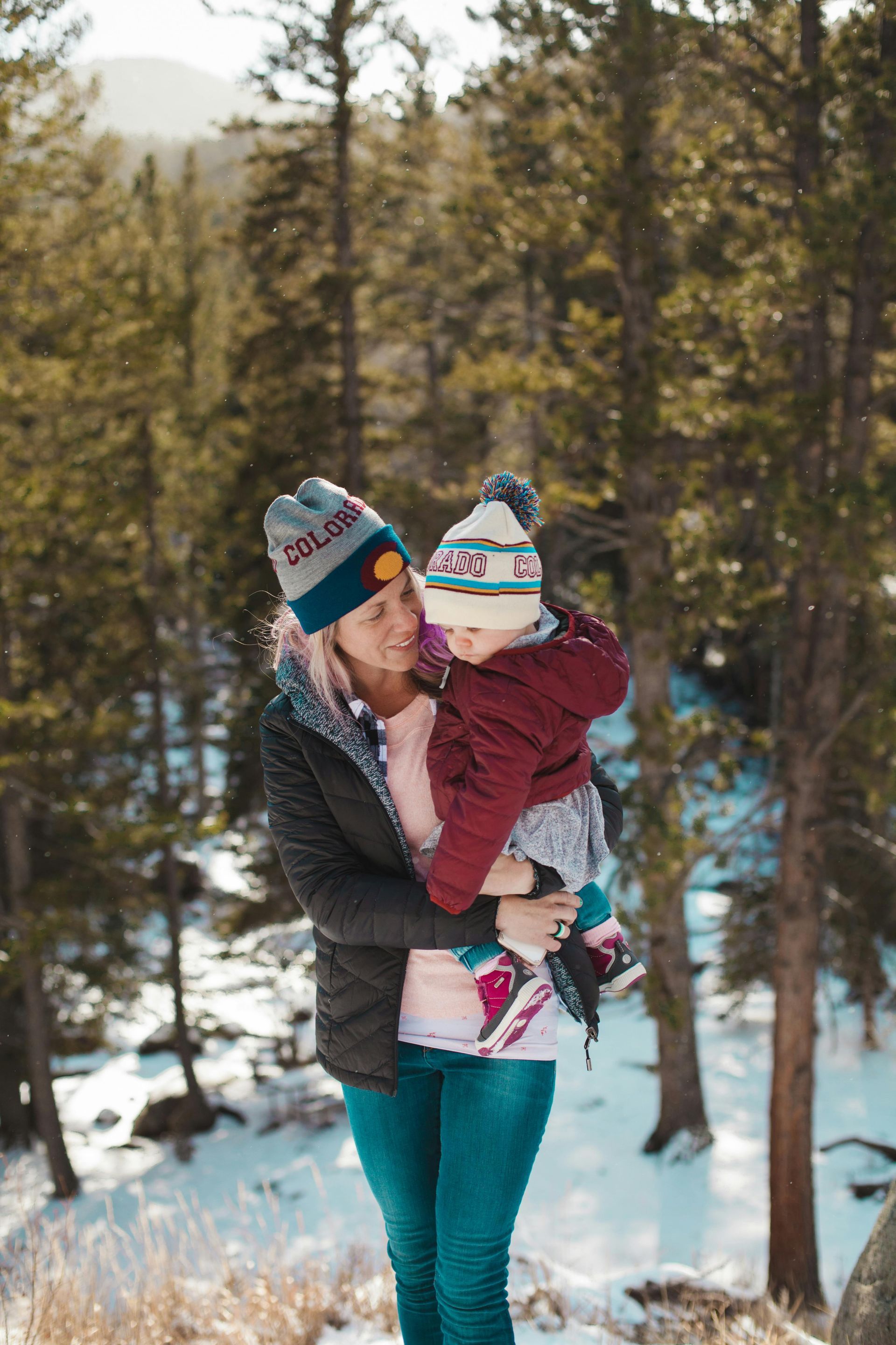 woman holding kid on snowy hike