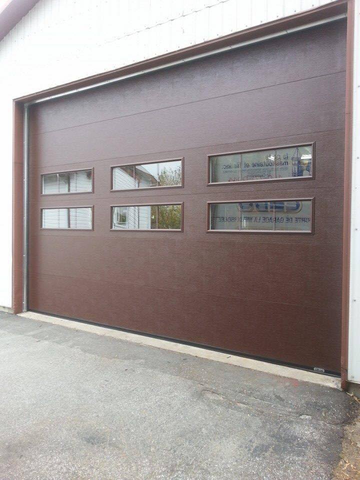 Une porte de garage marron avec trois fenêtres sur le côté d'un bâtiment.