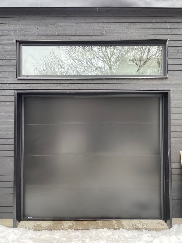 Une porte de garage noire avec une fenêtre au-dessus.