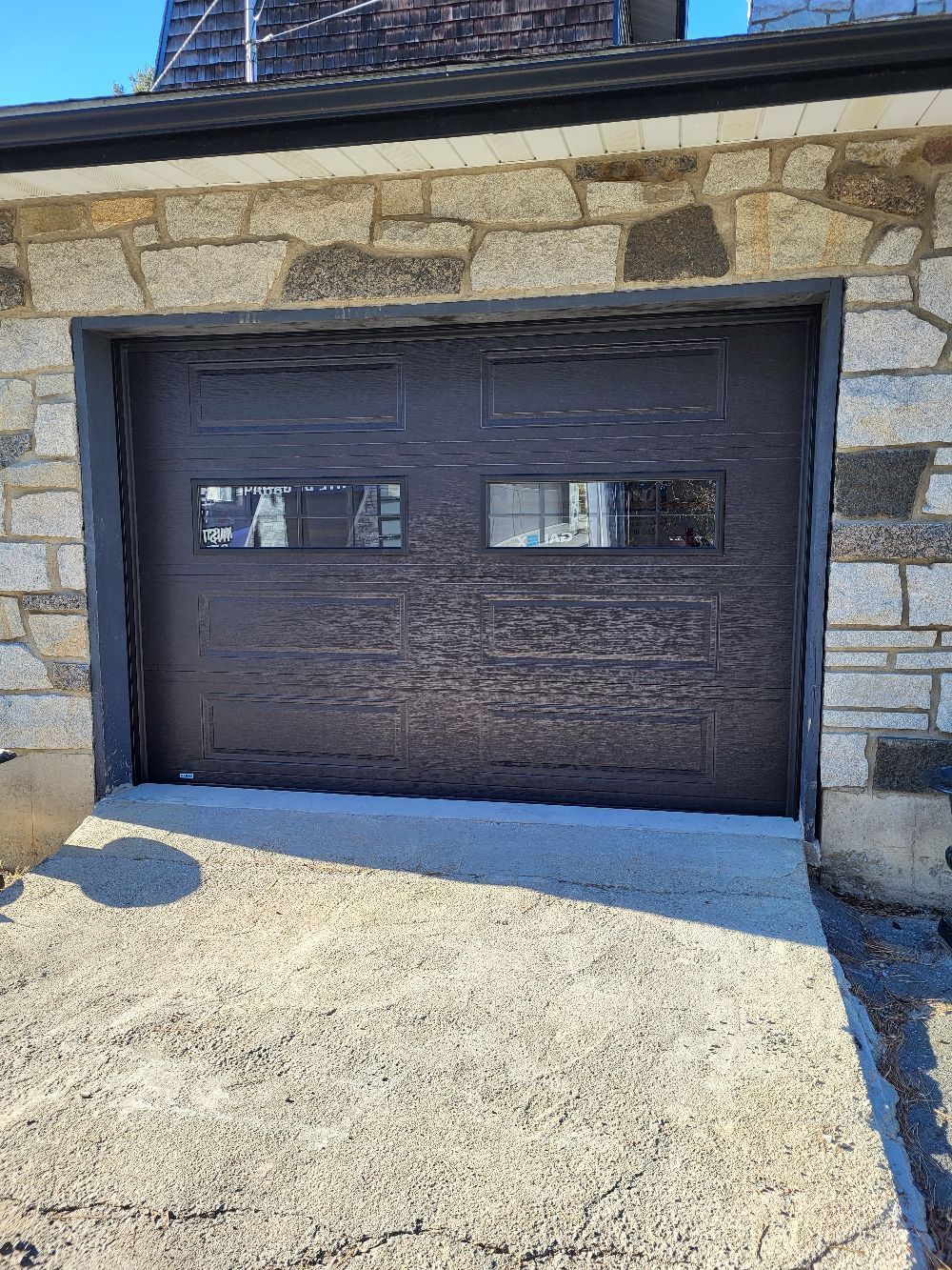 Une porte de garage marron se trouve devant un bâtiment en pierre.
