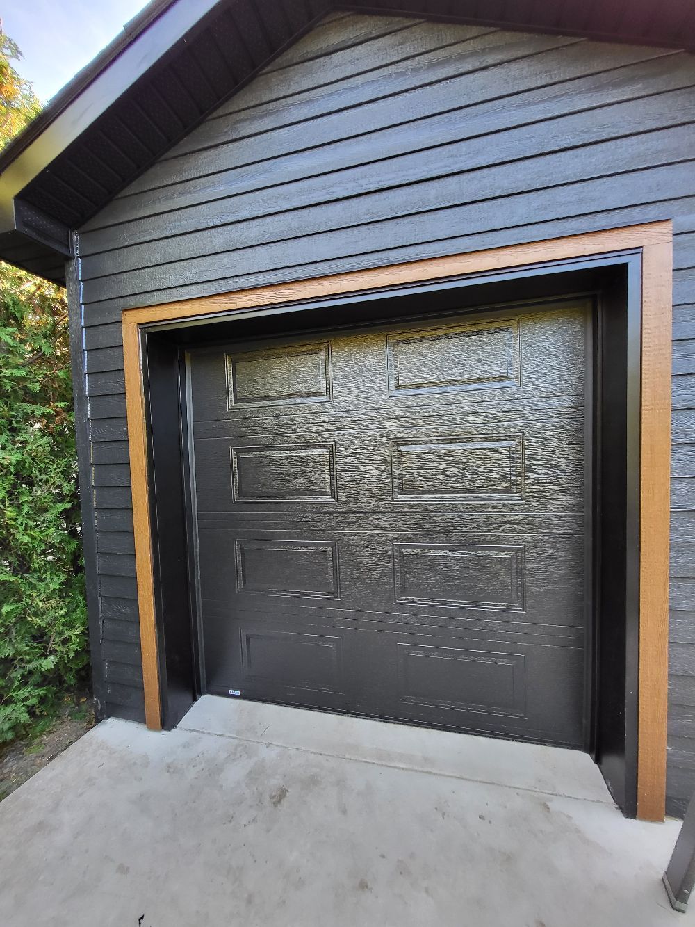 Une porte de garage noire se trouve sur le côté d'une maison.