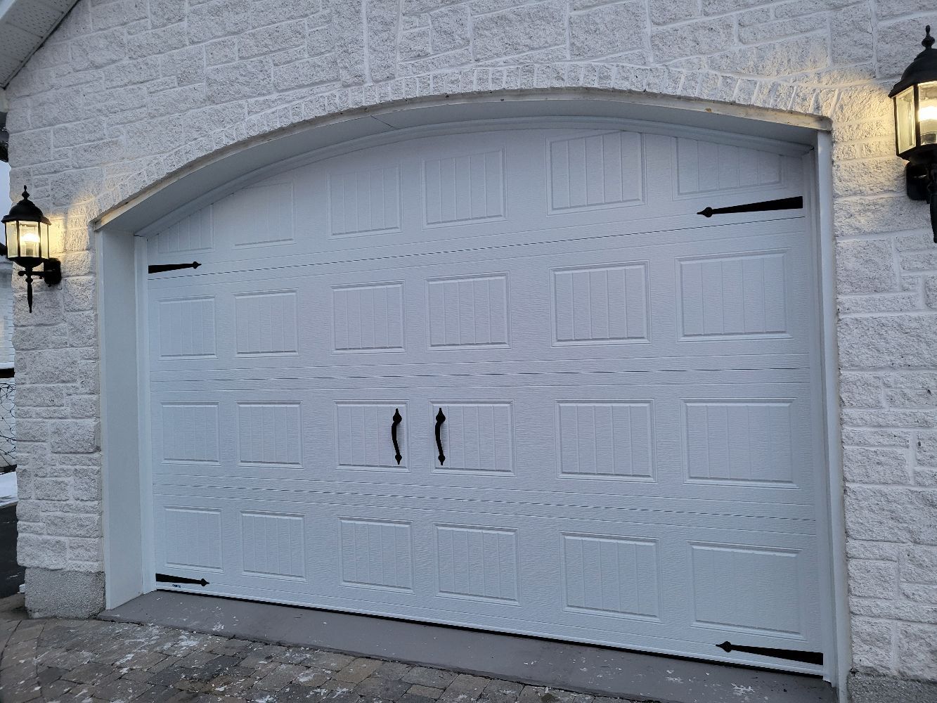 Une porte de garage blanche se trouve devant un bâtiment en briques.