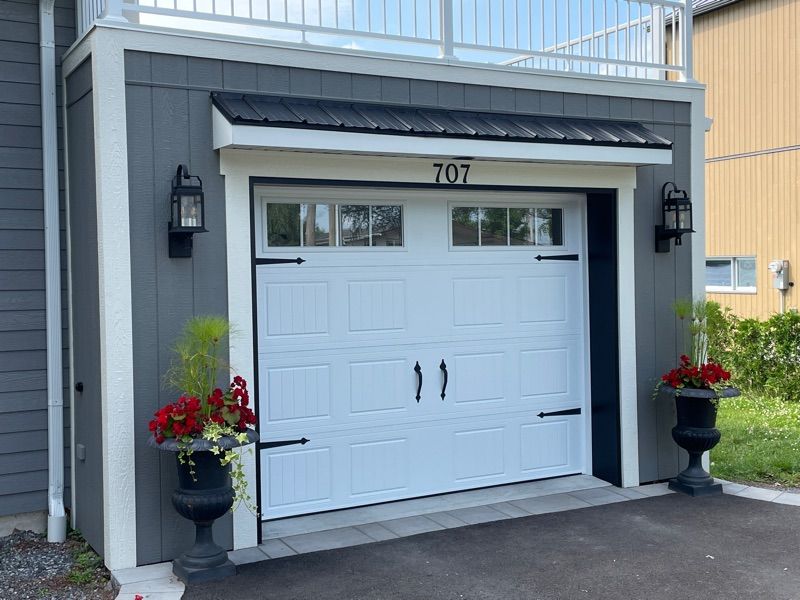 Une porte de garage blanche se trouve à côté d'une maison grise.
