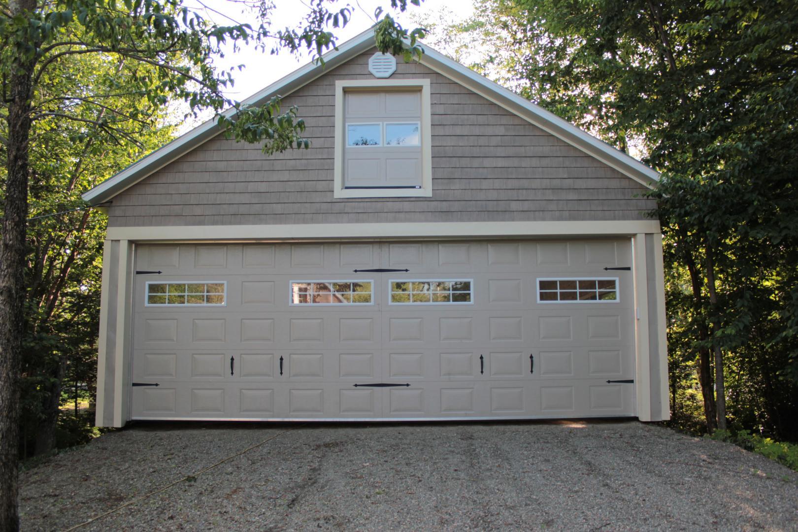 Un garage avec trois portes et une fenêtre au dessus.