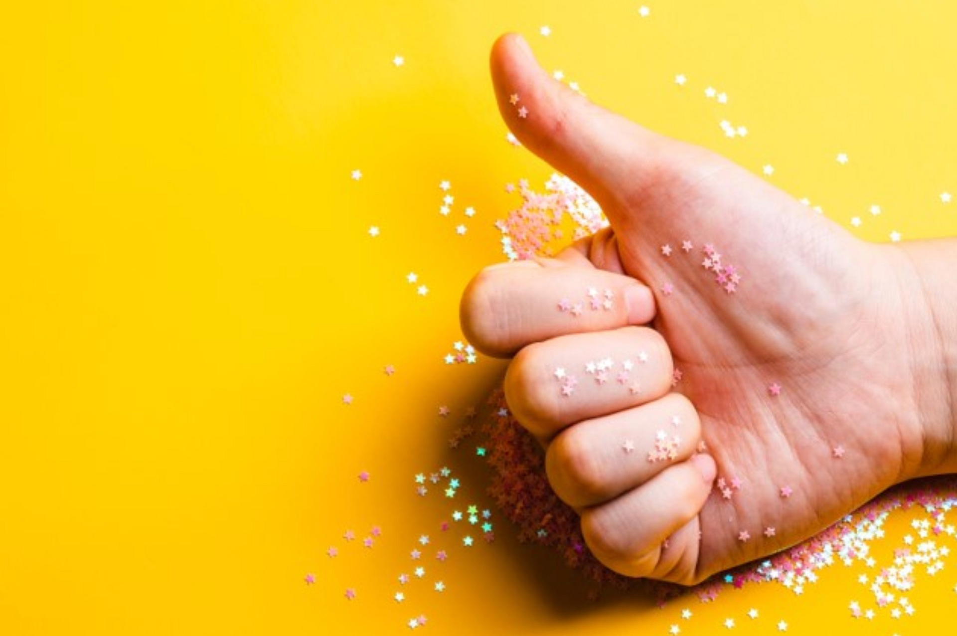 A hand is giving a thumbs up sign on a yellow background.