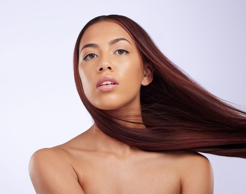 Woman with long, reddish-brown hair blowing in the wind, looking upwards with a neutral expression.