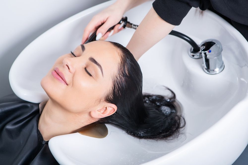Woman getting hair washed in salon sink.
