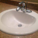 A bathroom sink with a chrome faucet on a granite counter top.