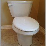 A white toilet is sitting on a tiled floor in a bathroom.