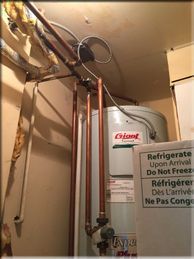 A water heater is sitting in a room next to a refrigerator.