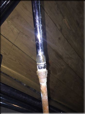 A close up of a rusty pipe on a wooden floor