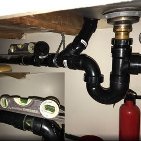 A sink with a lot of pipes underneath it and a fire extinguisher.