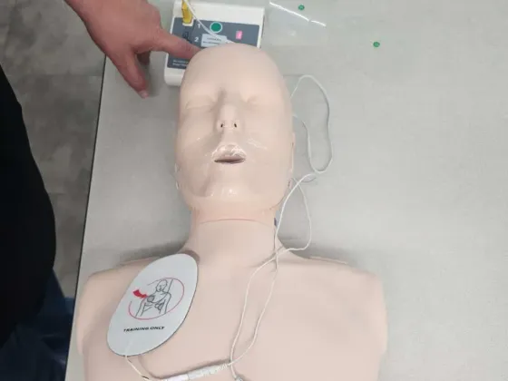 A person using an AED on a mannequin. AED pads are attached to the chest.