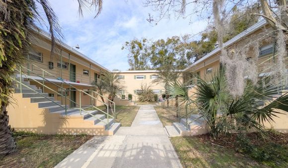 Courtyard apartment complex with exterior stairs, tan walls, and a walkway.