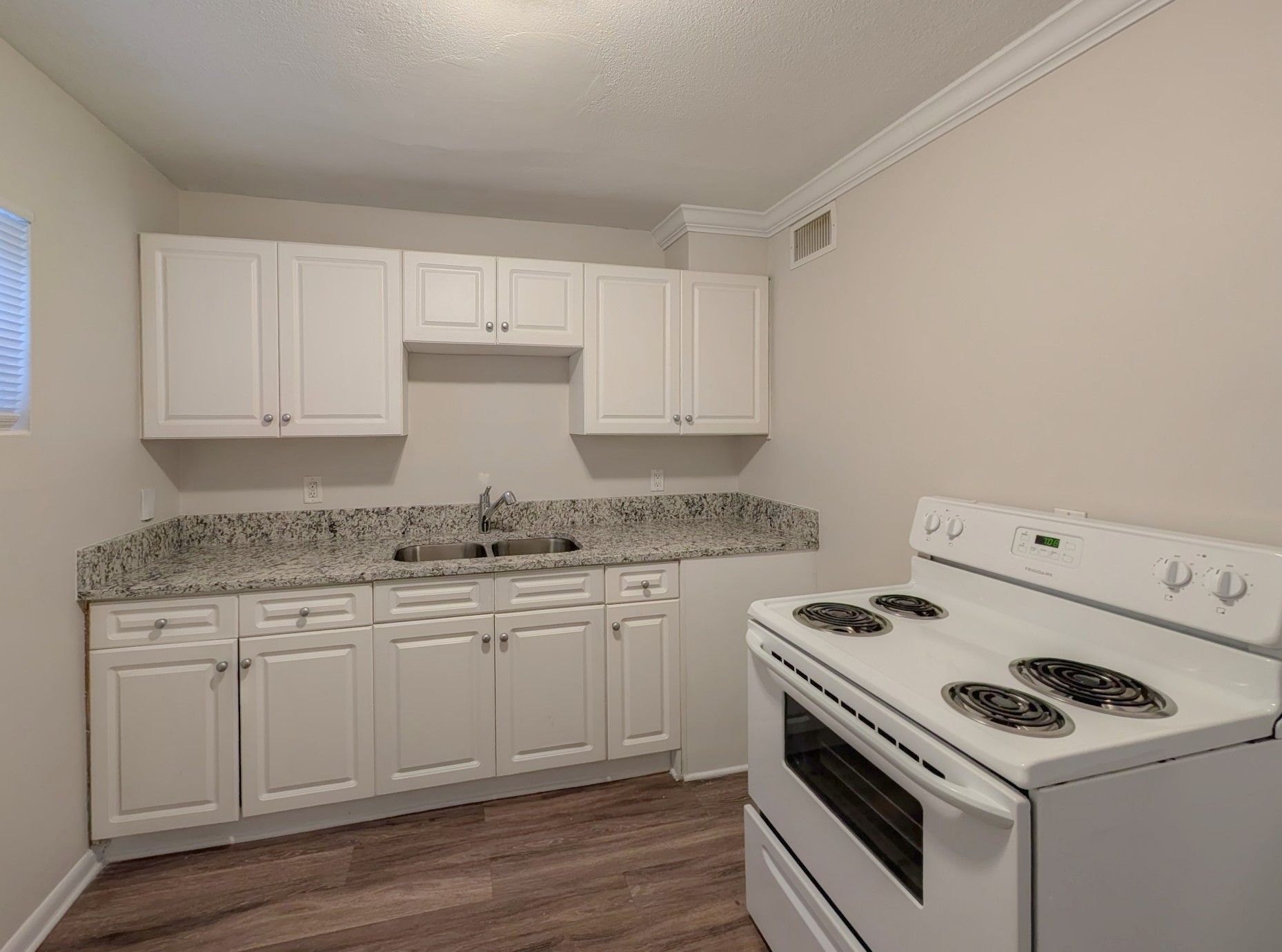 White kitchen with white cabinets, speckled countertops, and an electric stove.