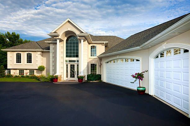 Two-story gray house with a black roof, white trim, and a ladder leaning against it, behind a white fence.