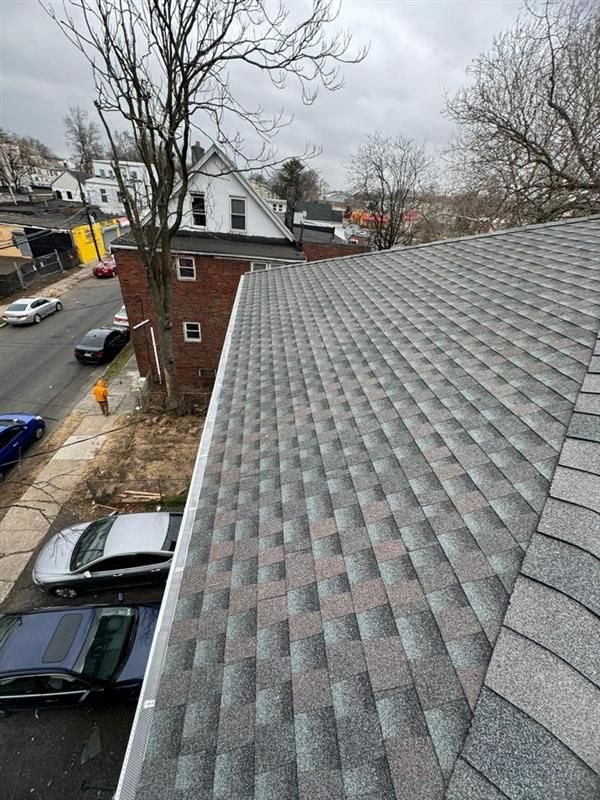 White house with dark gray roof and chimney against a cloudy sky.