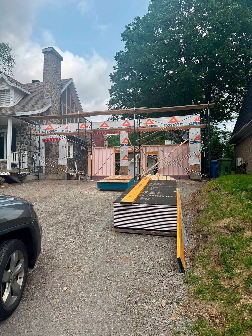 Maison en construction : ossature bois, matériaux de construction sur allée de gravier.