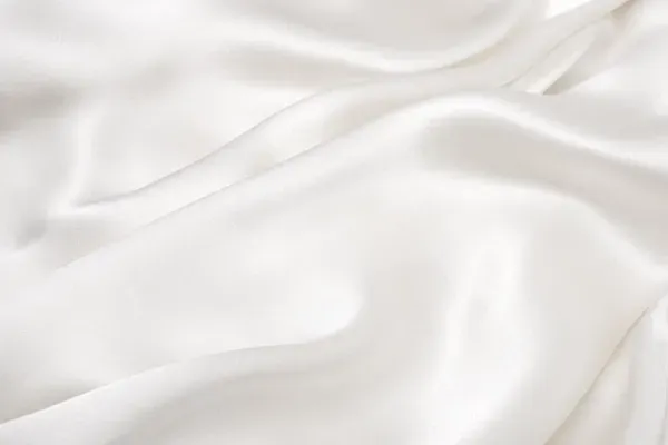 White, flowing silk fabric with soft, rippled texture and subtle highlights.