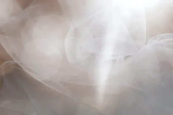 Soft, flowing white fabric tulle, with a blurred effect.