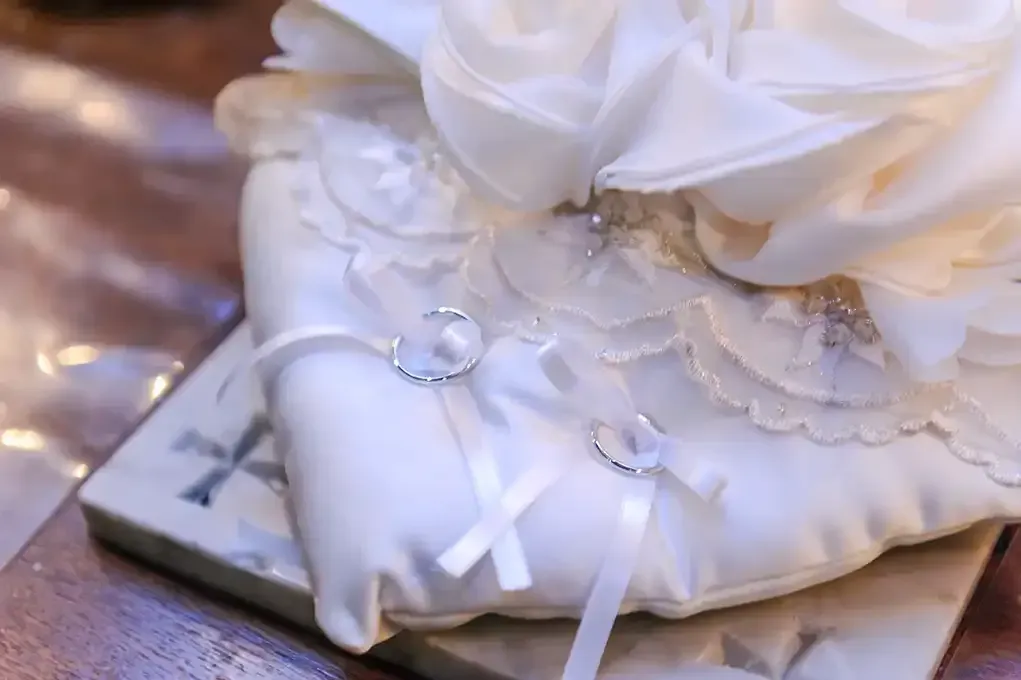 A pair of wedding rings sitting on top of a white pillow.