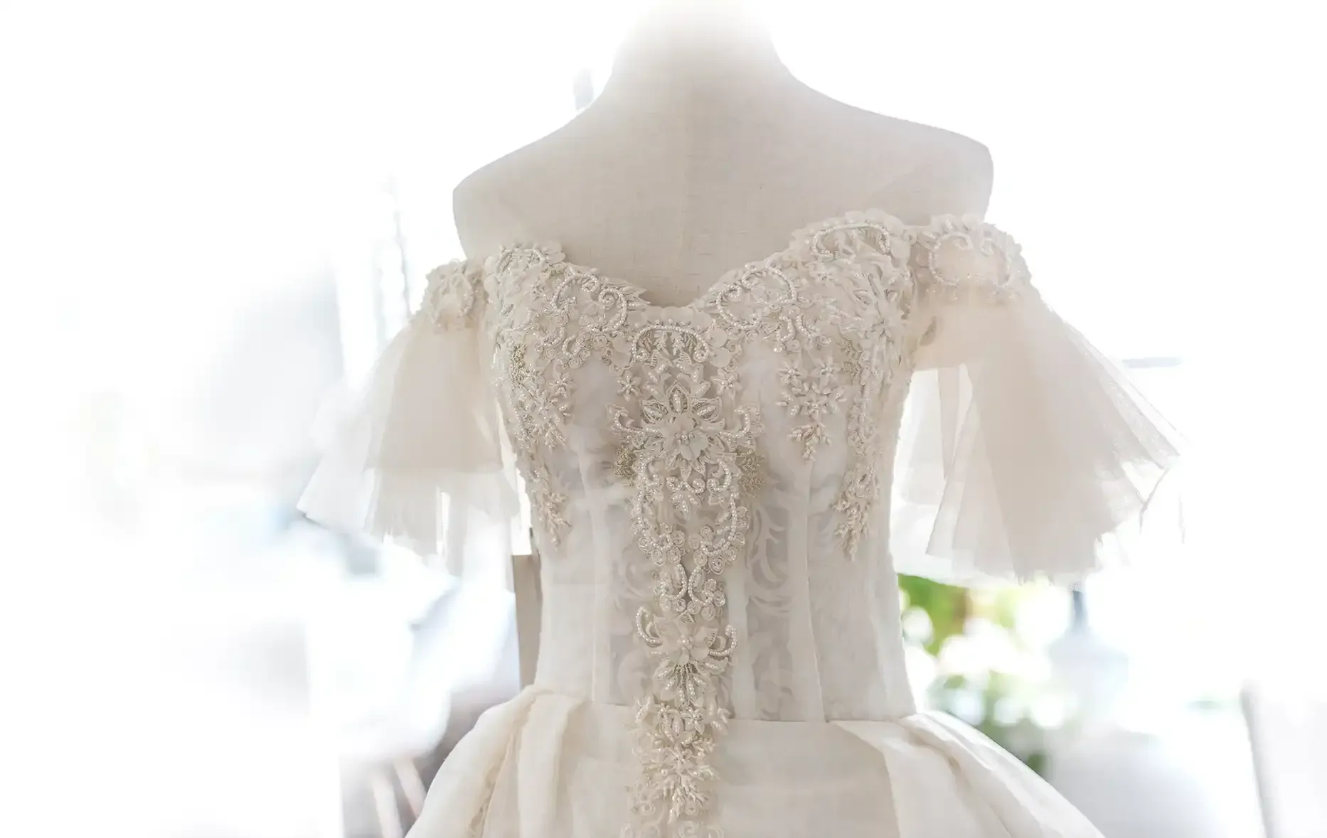 A white wedding dress is hanging on a mannequin.