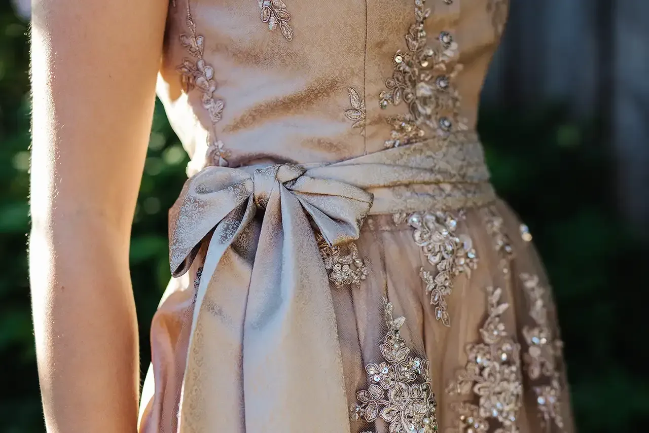 A woman is wearing a dress with a bow on the back.