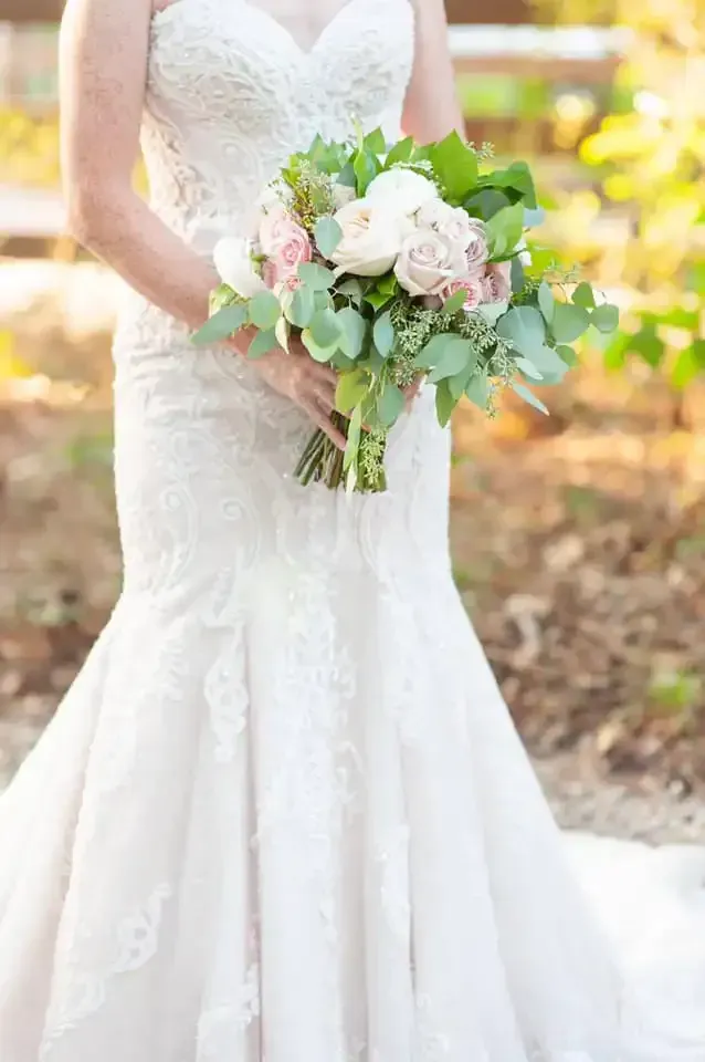 A bride in a wedding dress is holding a bouquet of flowers.