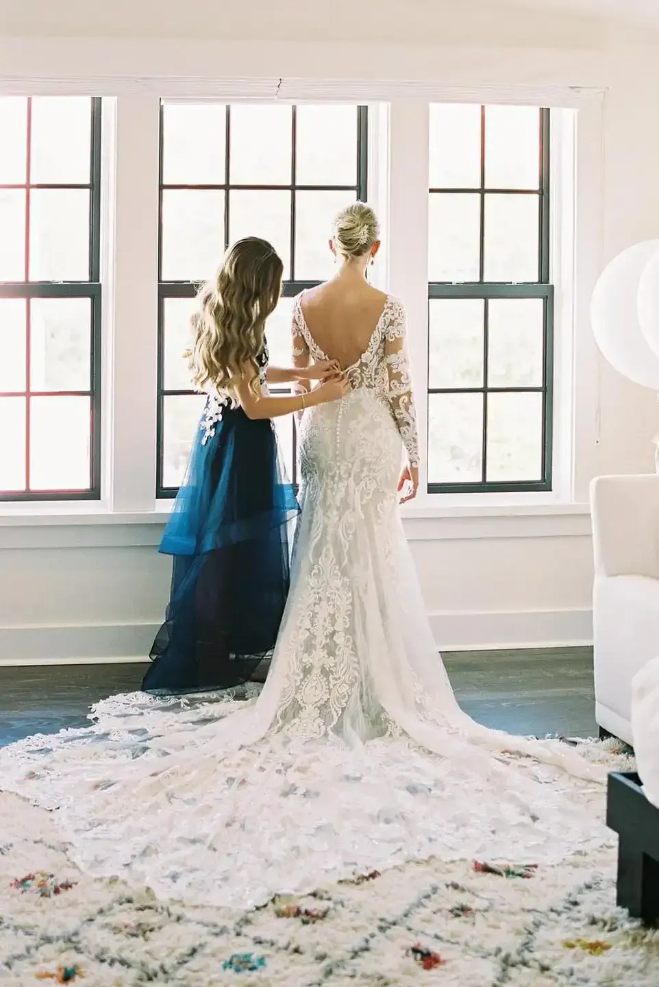 A woman is helping a bride get ready for her wedding.