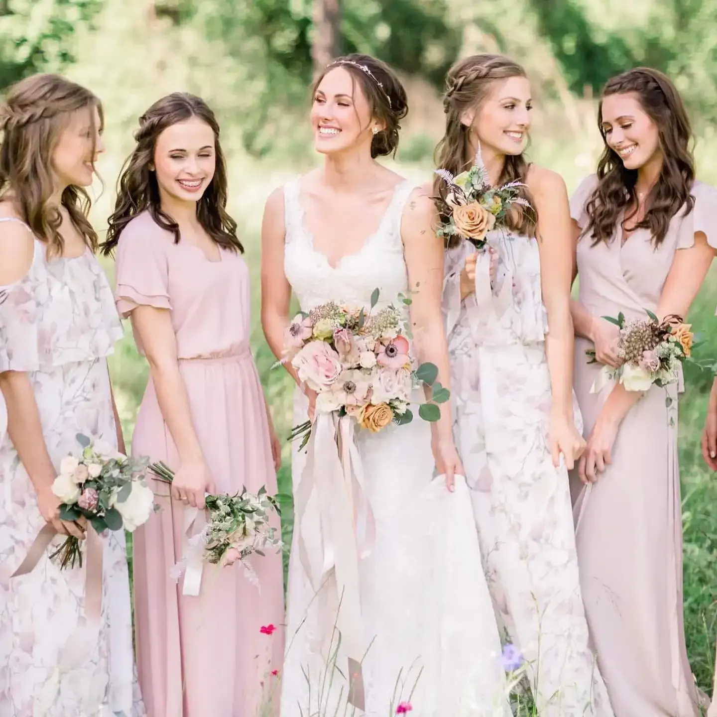 A bride and her bridesmaids are posing for a picture in a field.