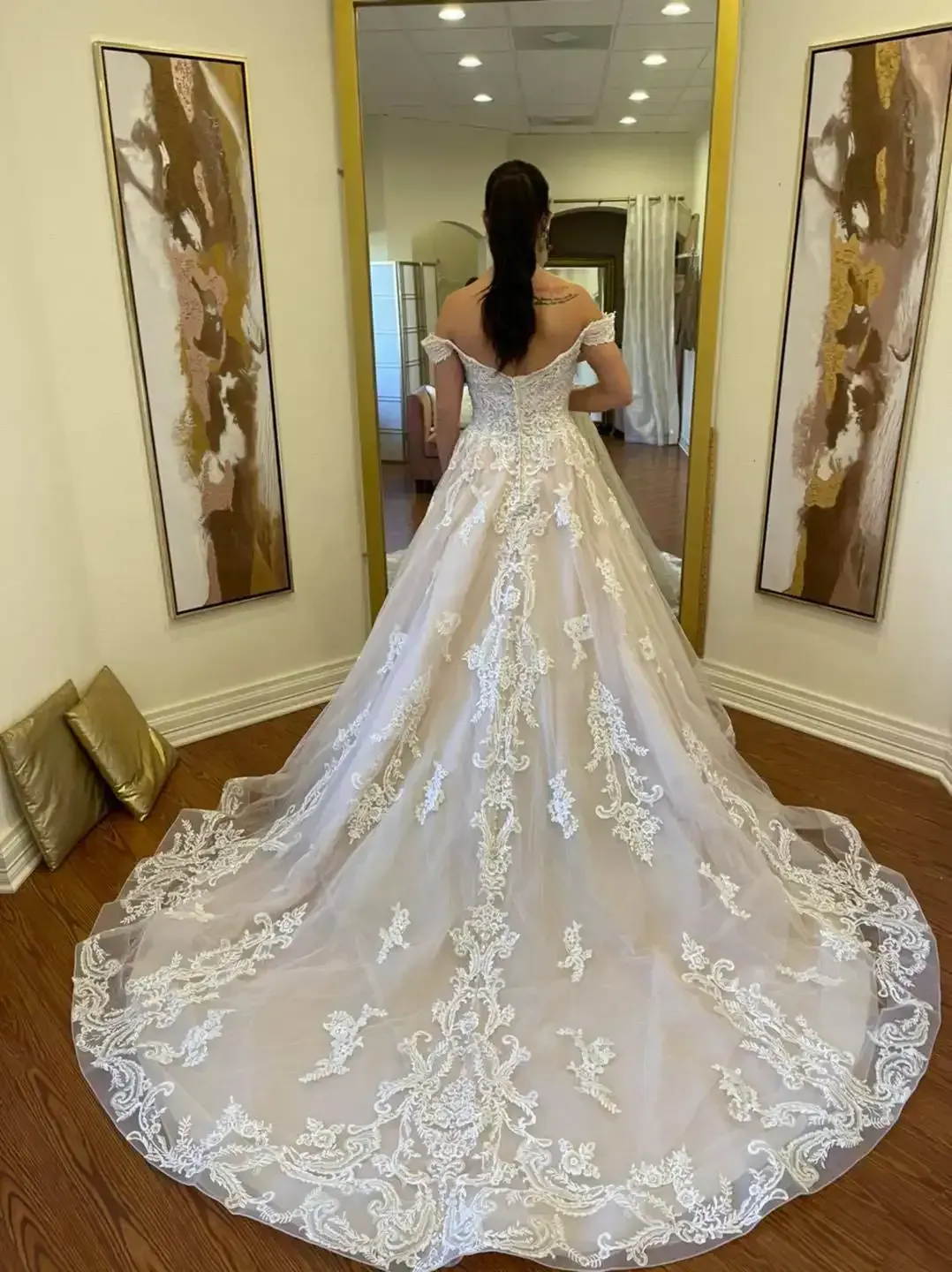 A woman is standing in a room wearing a wedding dress.