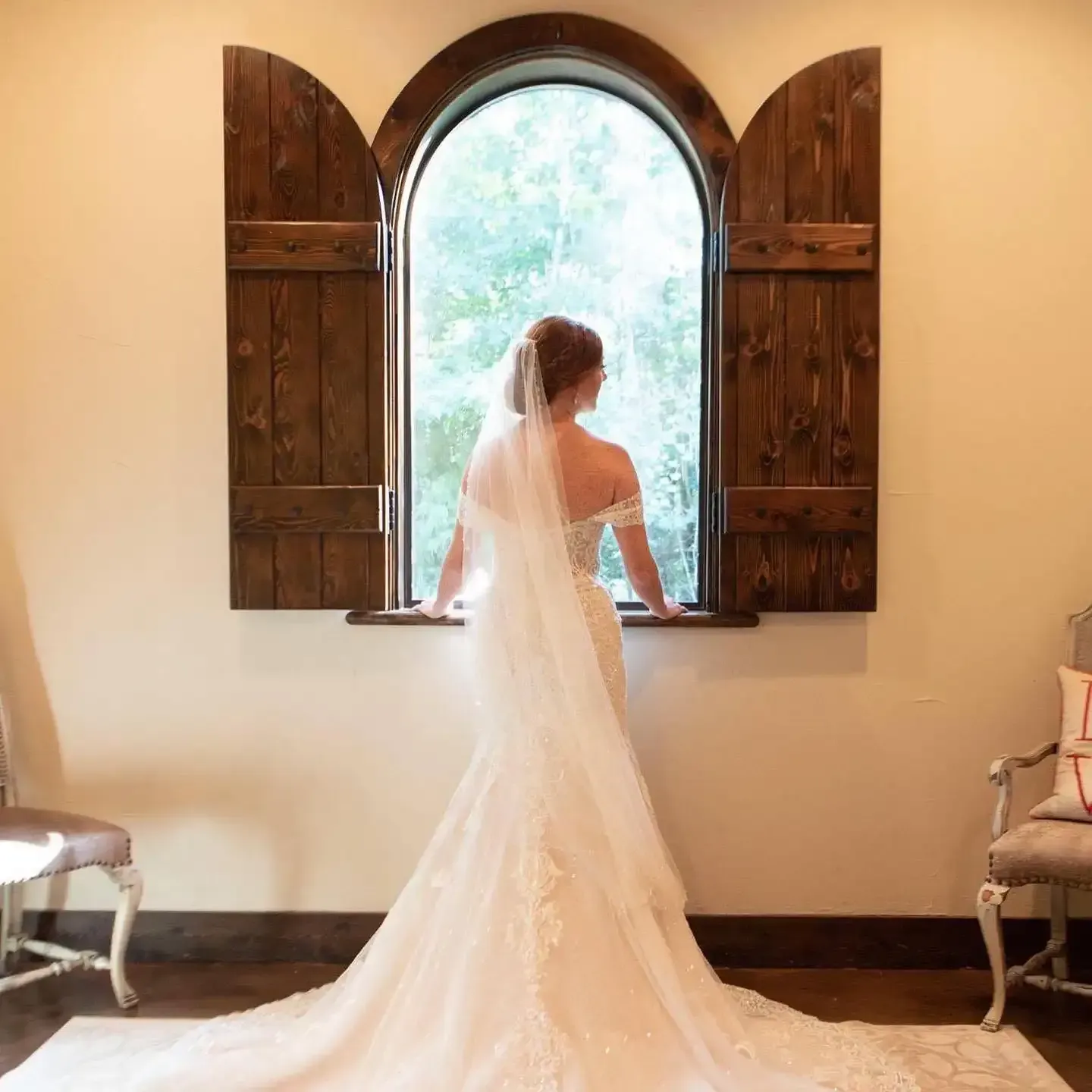 A bride in a wedding dress is looking out of a window.