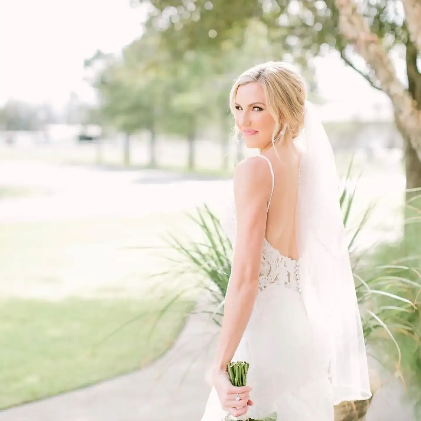 A bride in a white dress and veil is holding a bouquet of flowers.