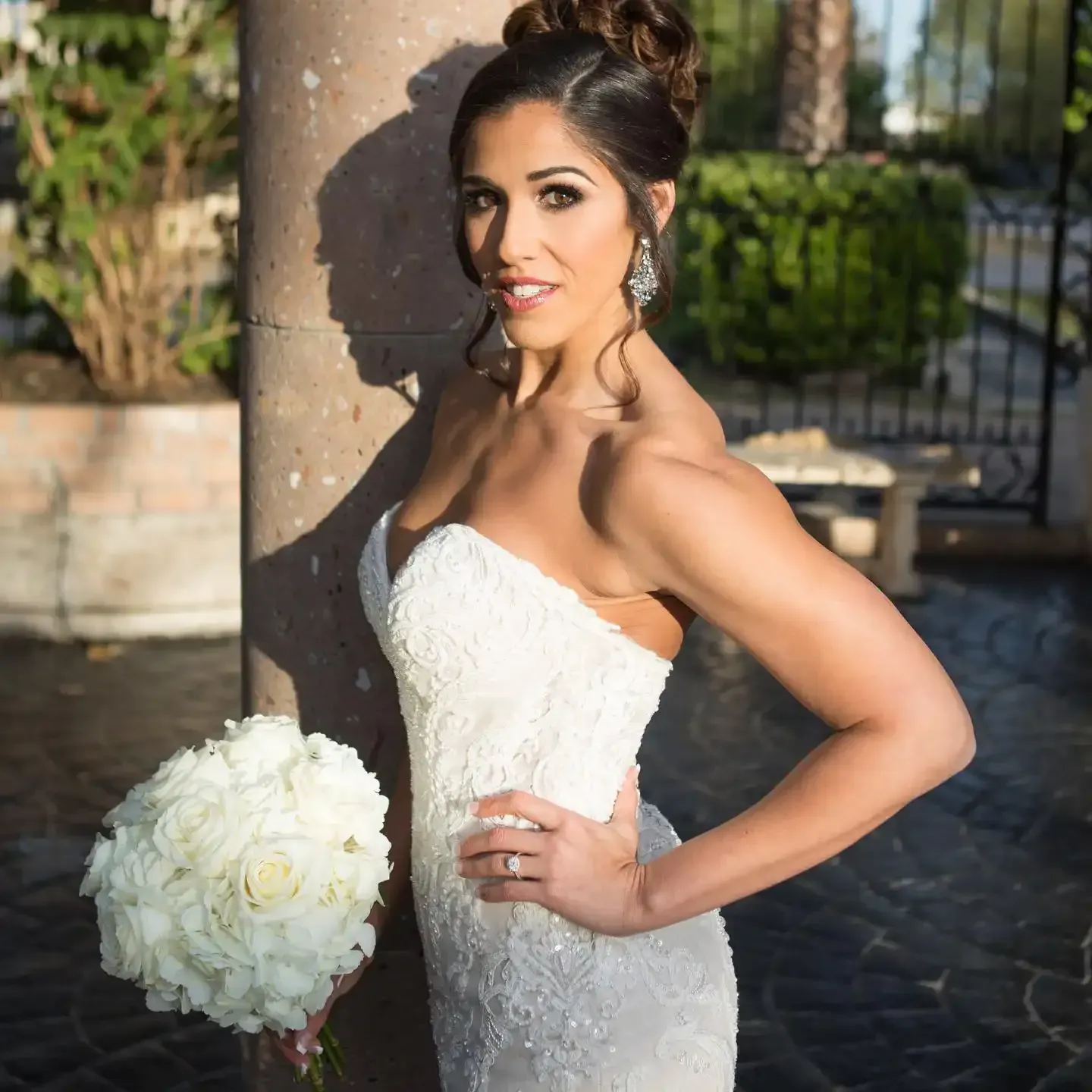 A woman in a white dress is holding a bouquet of white flowers