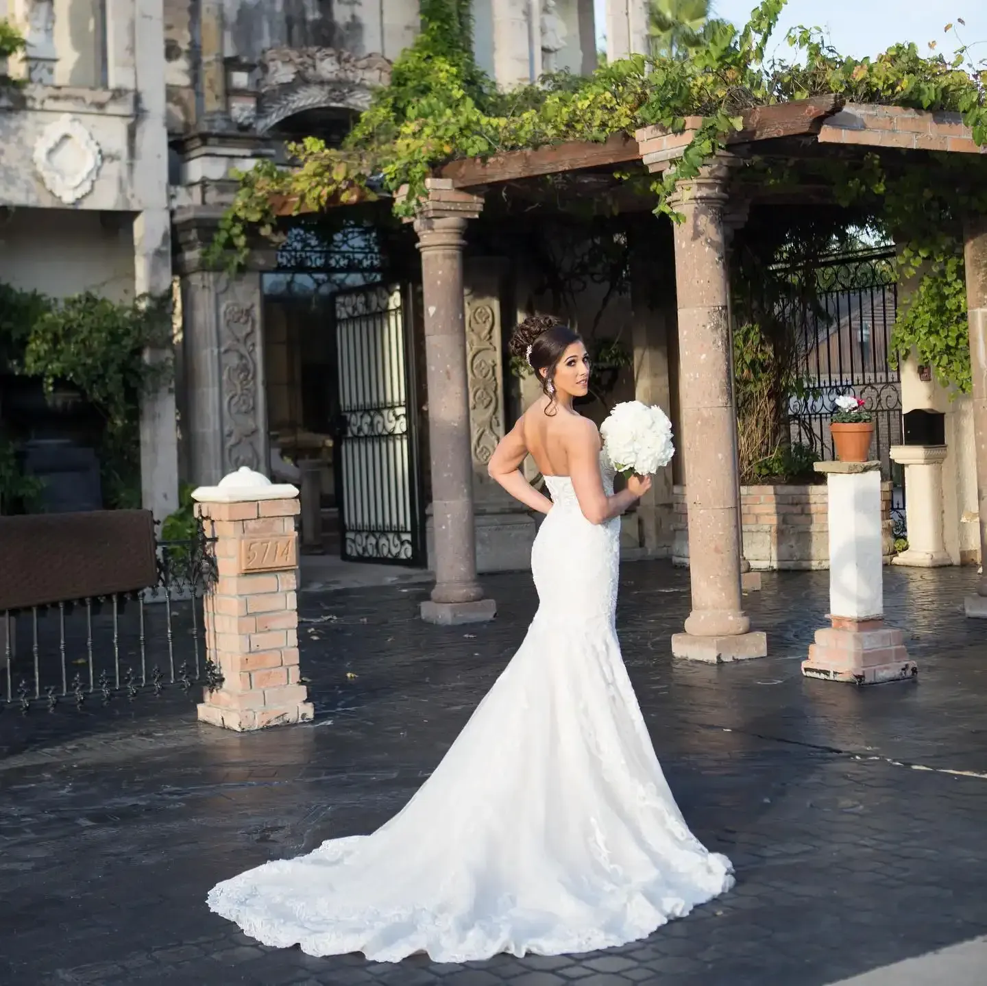 A woman in a white wedding dress is holding a bouquet of flowers