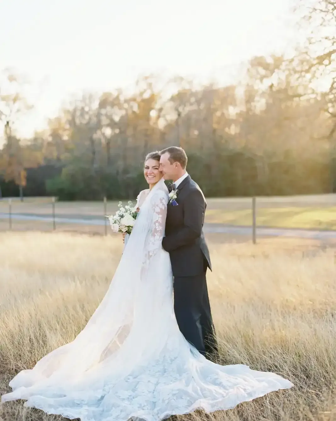 A bride and groom are posing for a picture in a field.