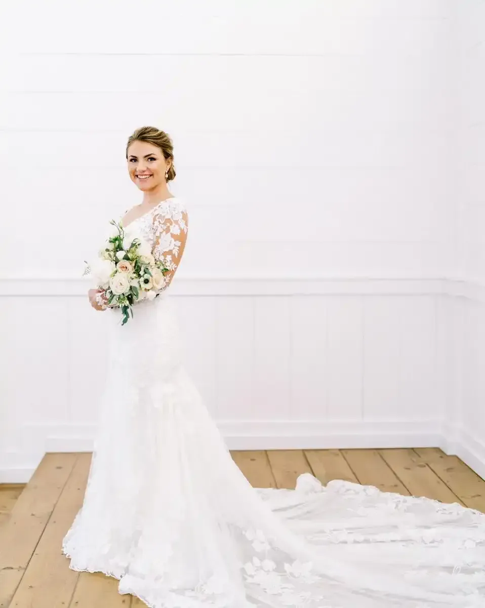The bride is wearing a long white dress and holding a bouquet of flowers.