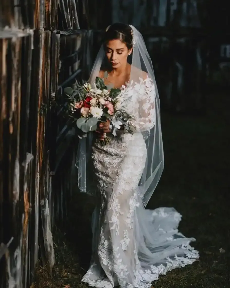 A bride in a wedding dress and veil is holding a bouquet of flowers.