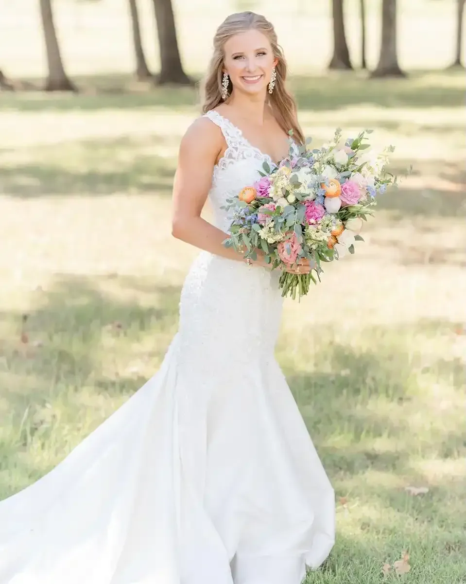 The bride is wearing a white wedding dress and holding a bouquet of flowers.