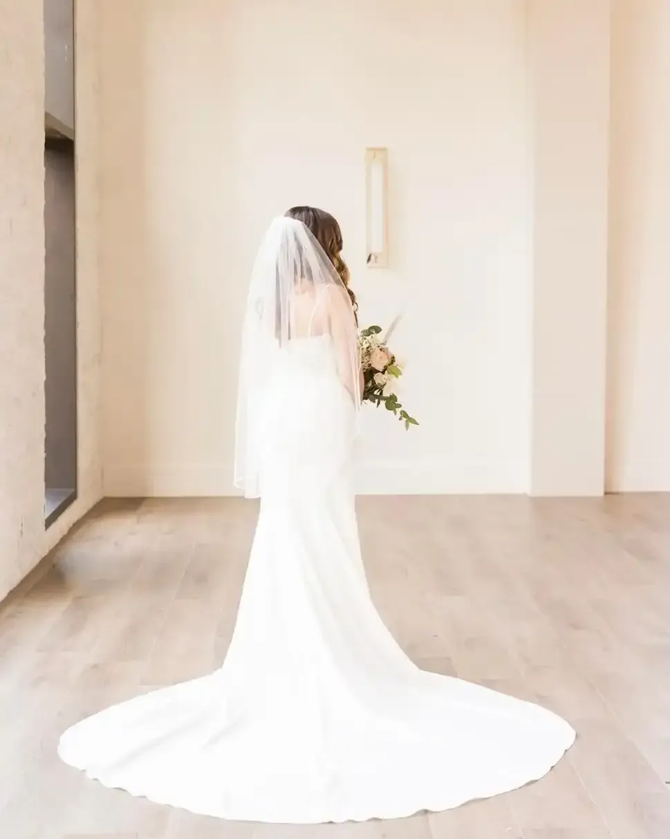 The bride is wearing a veil and holding a bouquet of flowers.