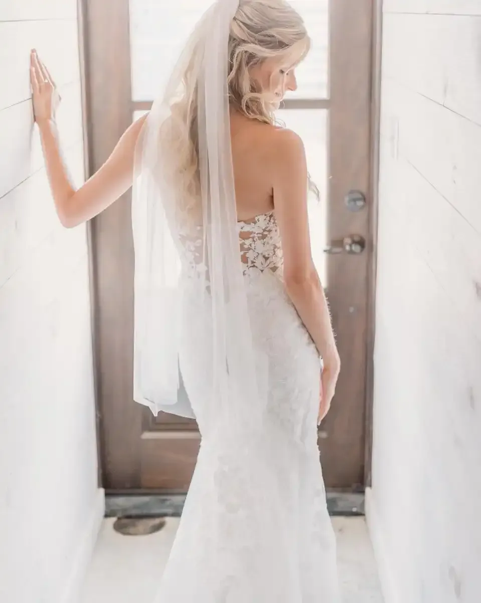 A woman in a wedding dress and veil is standing in front of a door.
